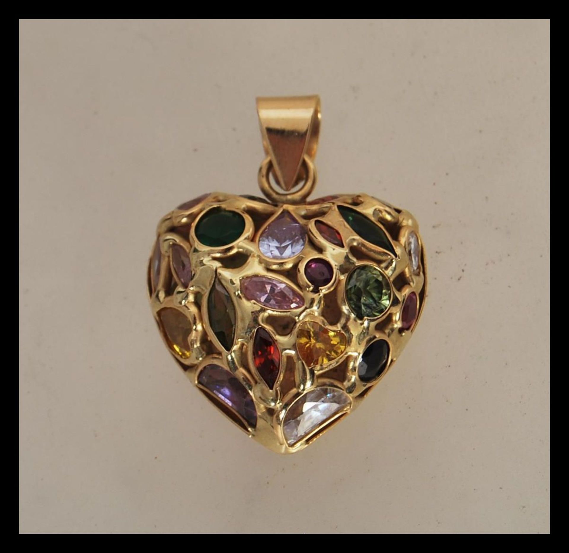 A stamped 750 gold pendant in the shape of a heart set with multi cut coloured stones. Weight 5.