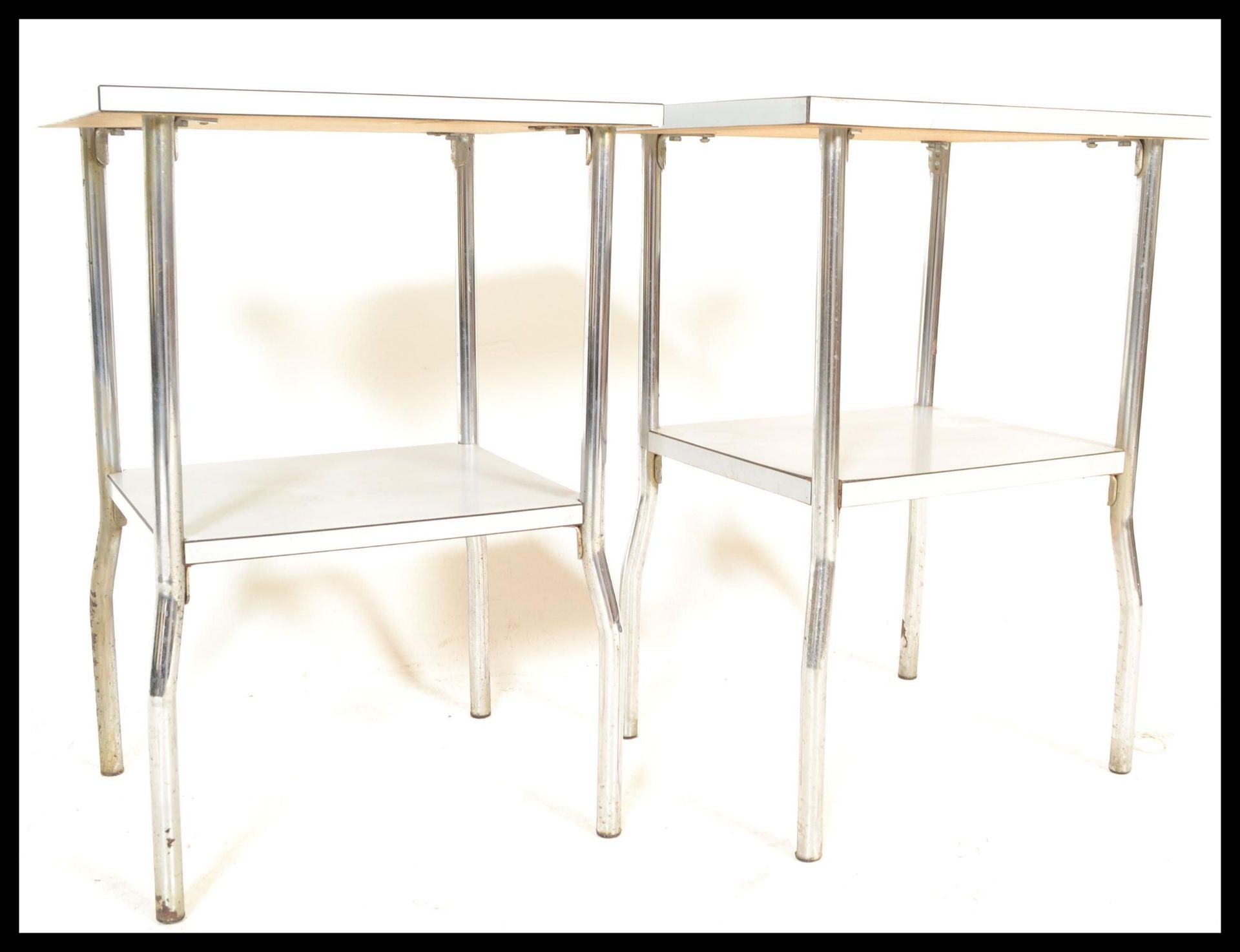 A pair of 20th Century retro industrial bedside tables having two graduating metal shelves raised on