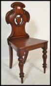 A 19th Century Victorian mahogany hall chair raised on turned legs with C scroll back and armorial