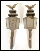 A pair of vintage brass carriage lamps, inset glass panels surmounted with eagle finials to the