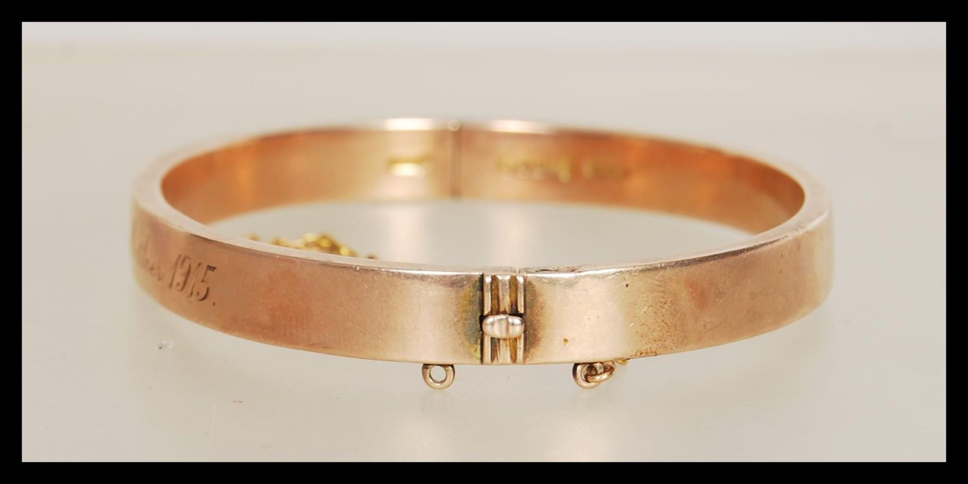 A hallmarked 9ct gold bangle having a hinged opening and safety chain. Hallmarked London 1914. - Image 2 of 4