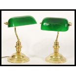 A pair of vintage 20th Century Bankers lamps raised on gilt brass circular bases with adjustable