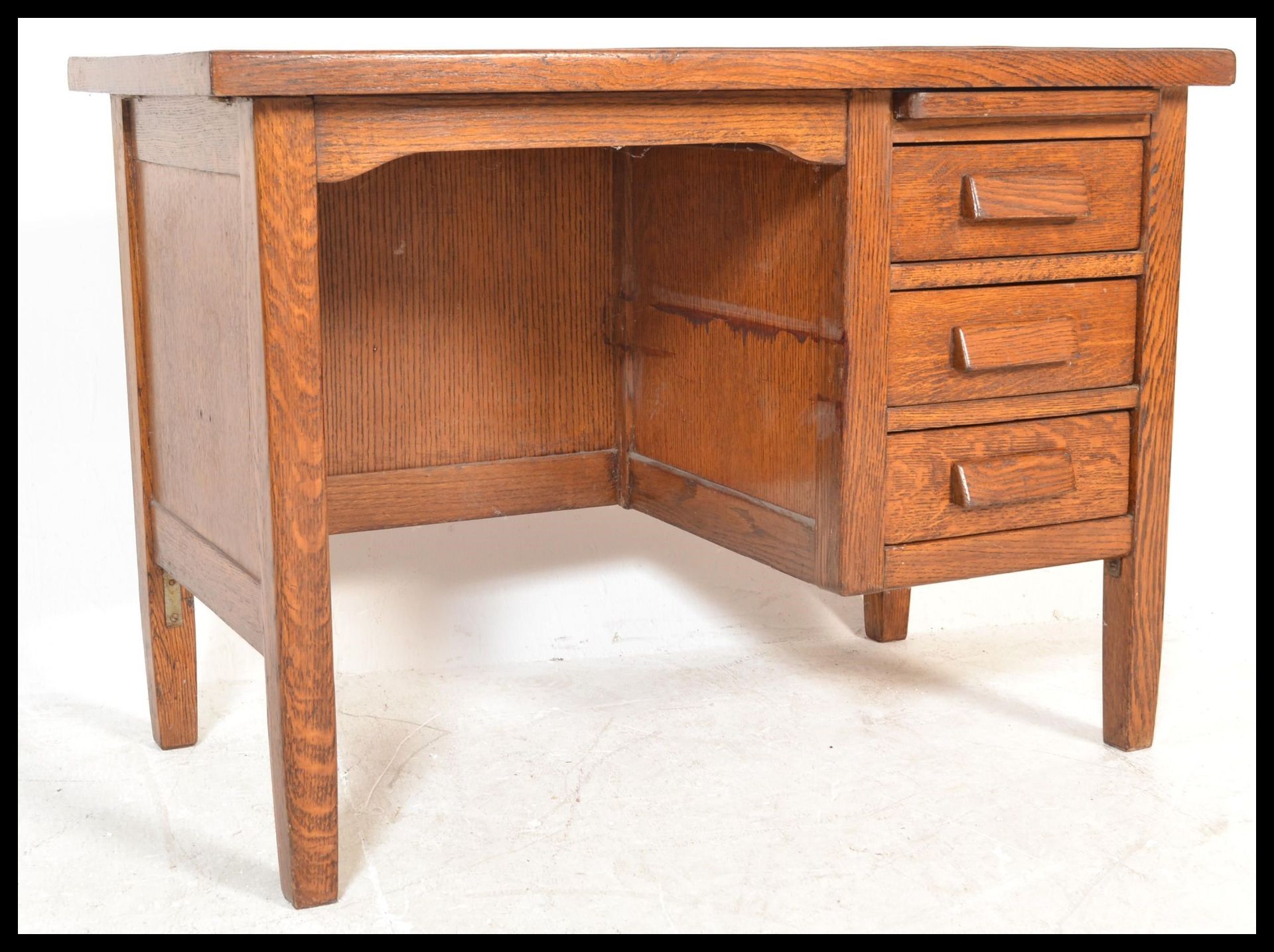 A small early 20th century oak single pedestal desk, having single pedestal with three drawers and