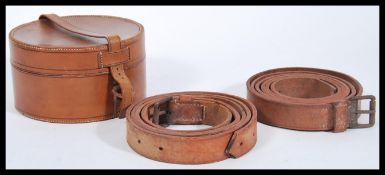 A group of vintage early 20th Century leather belts contained within a circular leather collar box.
