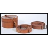 A group of vintage early 20th Century leather belts contained within a circular leather collar box.