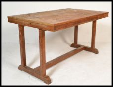 An early 20th Century Heals Art Deco oak refectory dining table raised on shaped base with table top