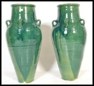 A large and impressive pair of Persian Sharab green glazed wine vessels of amfora form having four