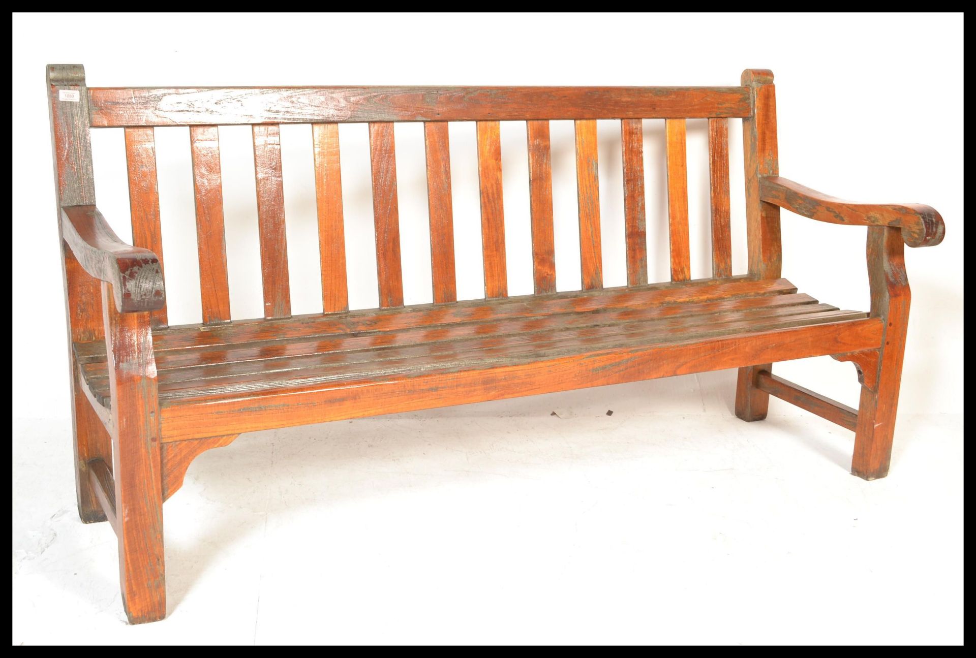 A good sized large solid teak wood garden bench of slatted form with shaped elbow rests either