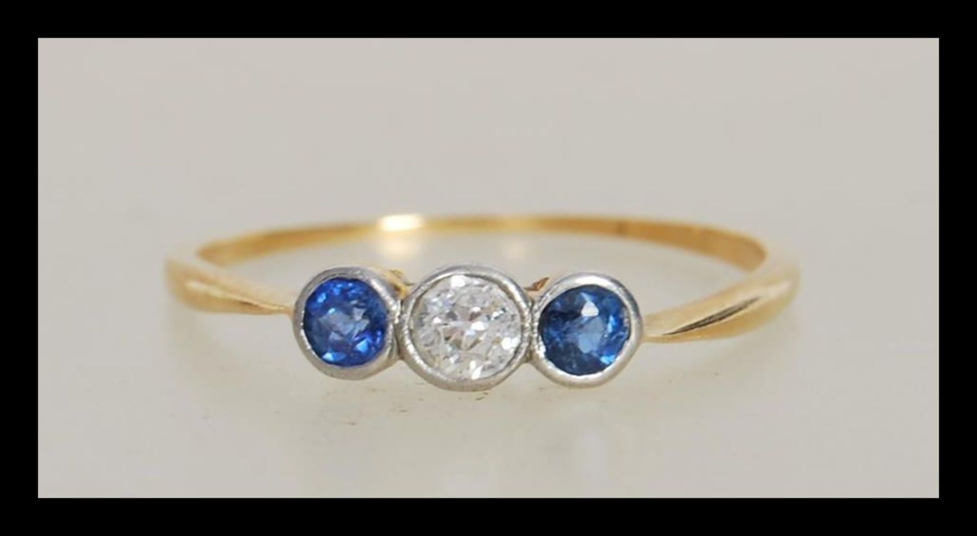 A 20th Century 18ct gold ring bezel set with a central round cut diamond flanked by two round blue
