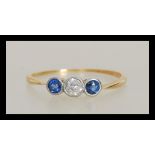 A 20th Century 18ct gold ring bezel set with a central round cut diamond flanked by two round blue