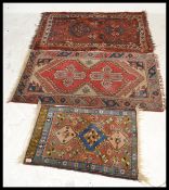A group of three Persian Islamic 20th Century carpet rugs to include a runner having a red ground