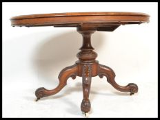 A Victorian walnut tilt top breakfast / loo table of oval form being raised on a  carved column with