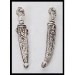 A pair of 20th Century silver white metal miniature daggers in sheafs having floral and leaf