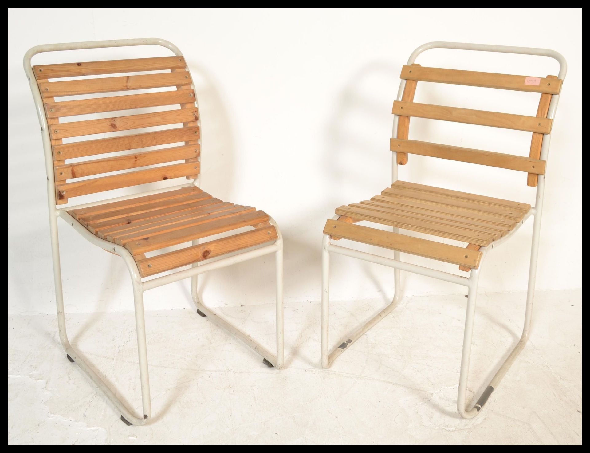 A pair of vintage retro 20th Century stacking chairs having slatted wood seats and backs raised on