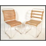 A pair of vintage retro 20th Century stacking chairs having slatted wood seats and backs raised on