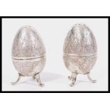 A pair of early 20th Century Arabic silver condiments pepperettes in the form of eggs raised om