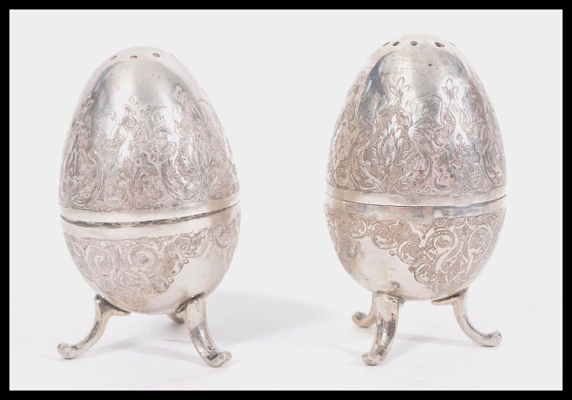 A pair of early 20th Century Arabic silver condiments pepperettes in the form of eggs raised om