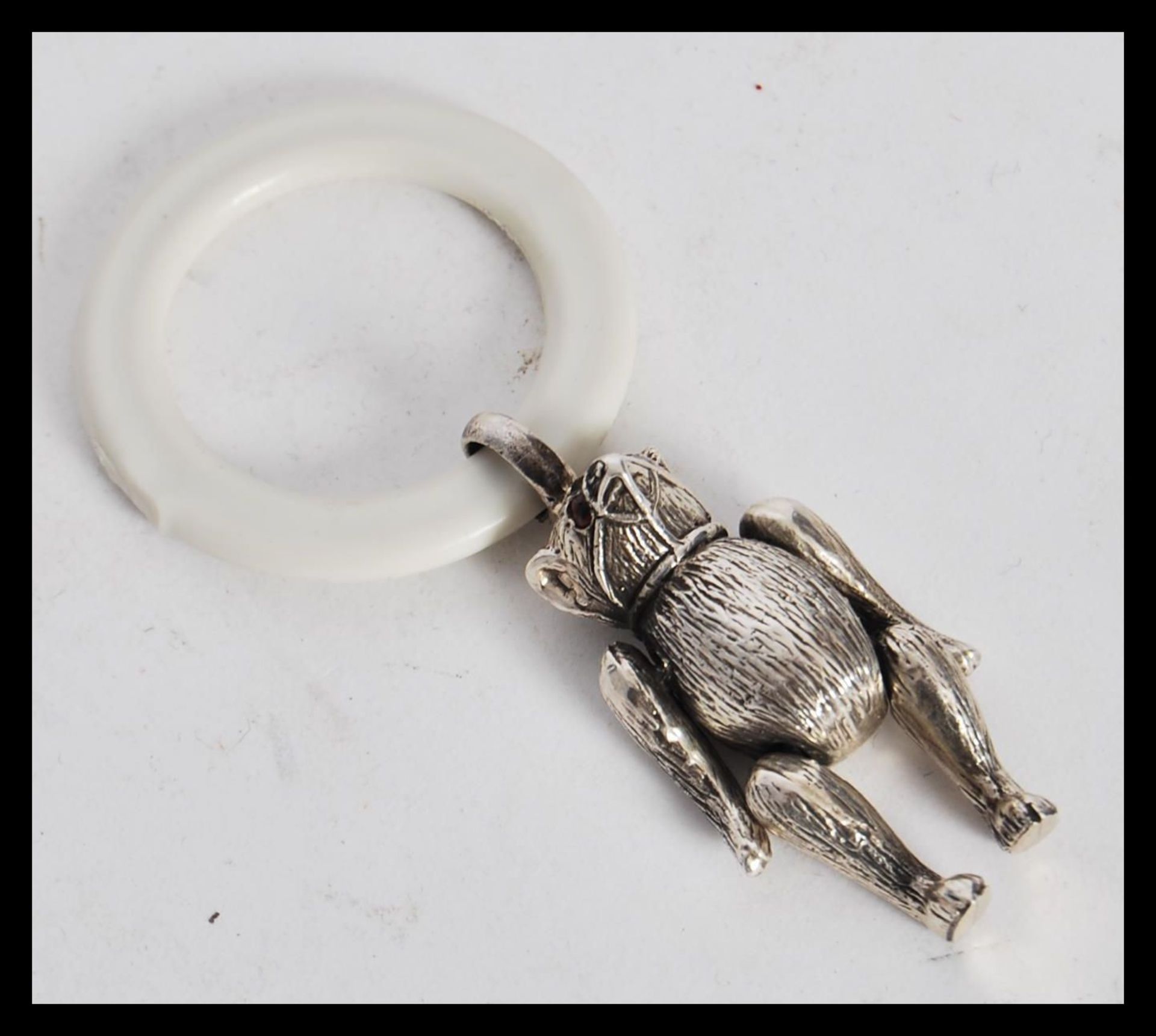 A sterling silver babies teething ring figurine in the form of a bear having articulated legs and