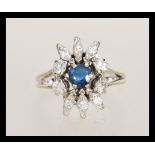 An 18ct white gold ring sapphire and diamond cluster ring having a central round cut sapphire