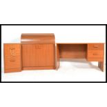 A 1970's retro mid 20th century teak office suite comprising a pedestal desk with a roll top