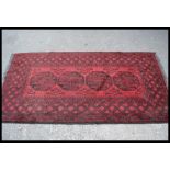 A 20th Century Persian Islamic floor rug / carpet having a red ground with black geometric borders