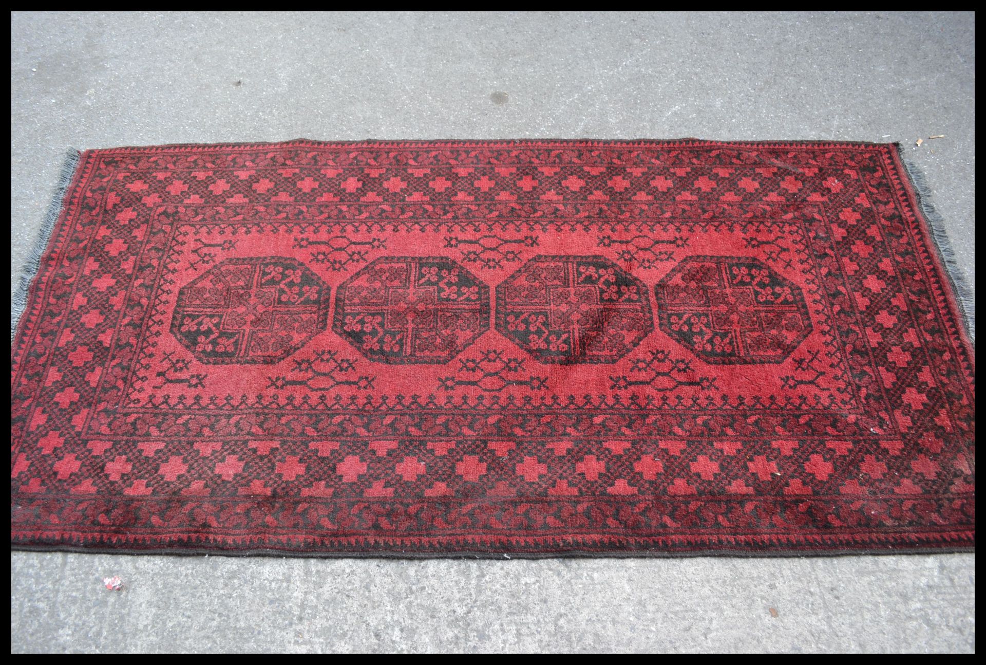 A 20th Century Persian Islamic floor rug / carpet having a red ground with black geometric borders