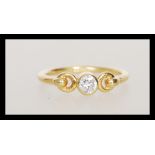 A hallmarked 18ct gold ring set bezel set with a brilliant cut diamond with decorative looped