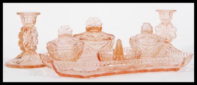 An early 20th Century Art Deco peach glass dressing table set consisting of three lidded pots, two
