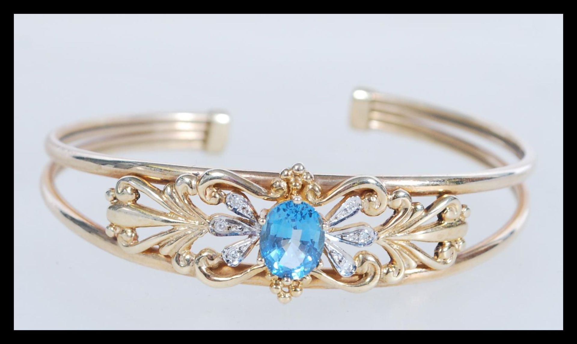 A hallmarked 9ct gold topaz and diamond cuff bangl