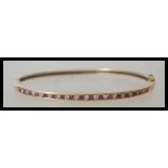 A 9ct 375 stamped bangle bracelet having a pave set alternating line of rubies and diamonds. The