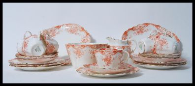 An early 20th Century tea service by Aynsley having a printed scrolled and floral orange pattern,