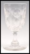 A large 19th Century faceted glass wine glass of tall form raised on a circular foot with faceted