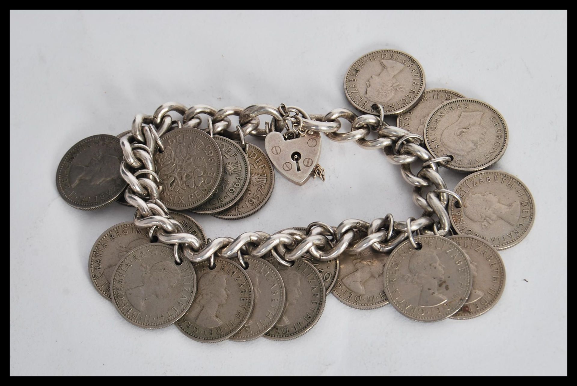 A sixpence coin bracelet on a curb link chain with a heart lock. Lock stamped silver. Gross weight