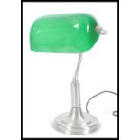 A vintage retro 20th Century bankers lamp having an adjustable green glass shade raised on stepped
