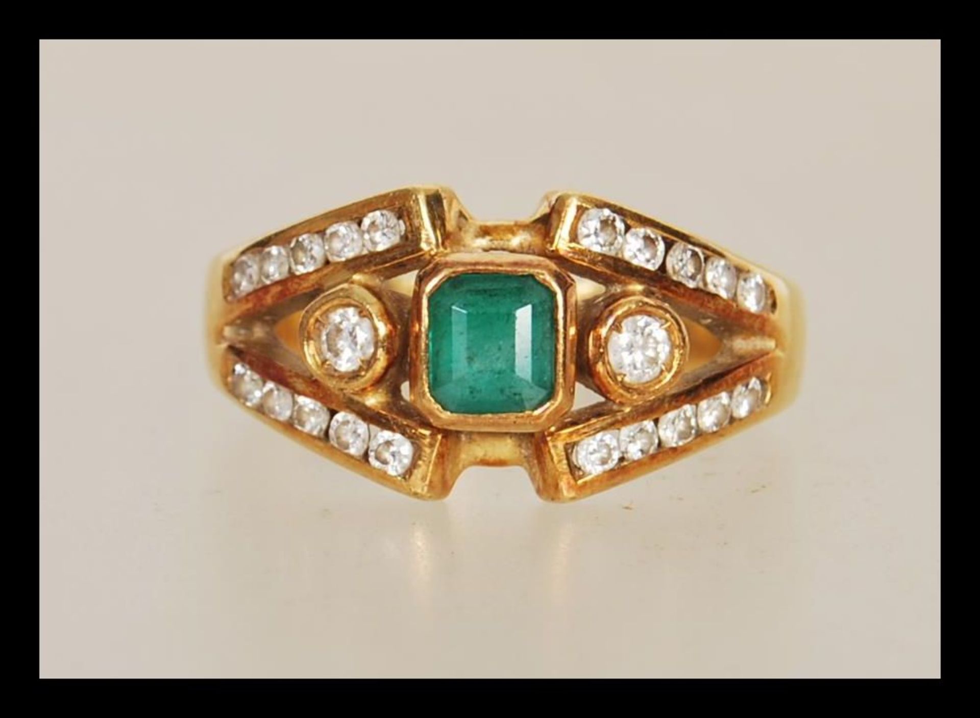 A stamped 750 18ct gold ladies dress ring set with a square cut emerald within a split shank