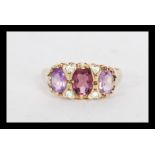 A hallmarked 9ct gold three stone amethyst ring in a Gypsy setting having white stones spacers.
