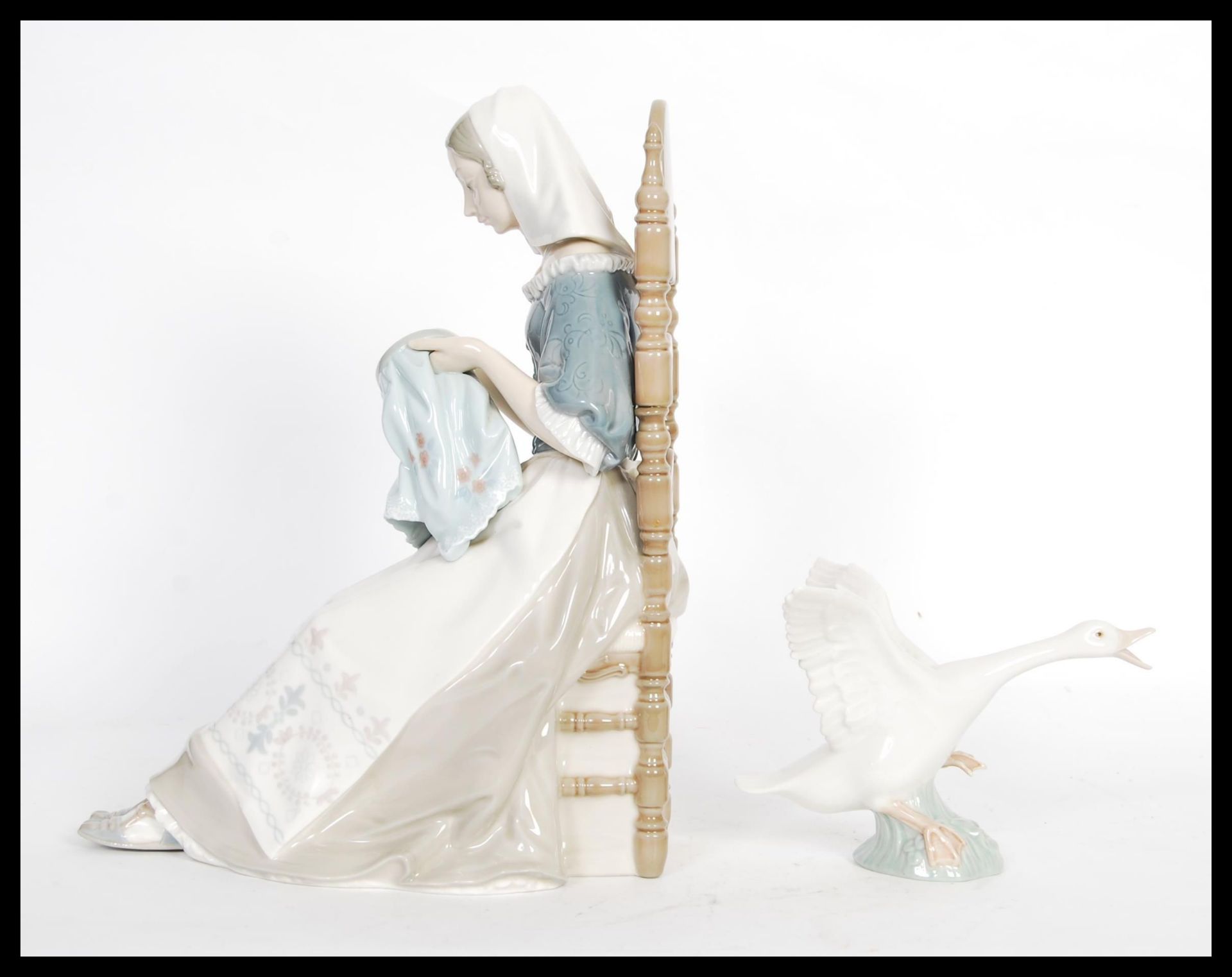 A Lladro porcelain figure depicting a woman doing embroidery seated in a chair along with a figurine - Bild 2 aus 4