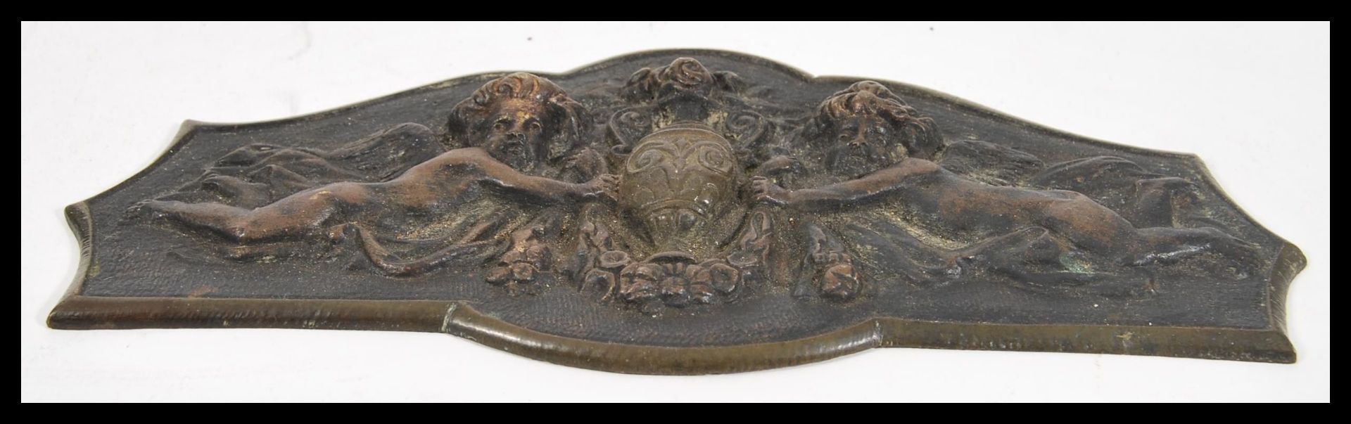 A 20th Century cast brass plaque having raised decoration of two cherubs bearing an urn and a floral - Bild 2 aus 3