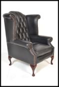 A contemporary antique style black leather chesterfield armchair being raised on cabriole legs