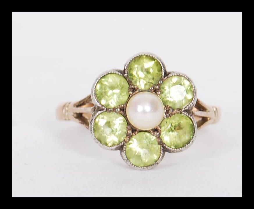A stamped 9ct gold ring having a flower head seat with round cut peridots with a pearl to the