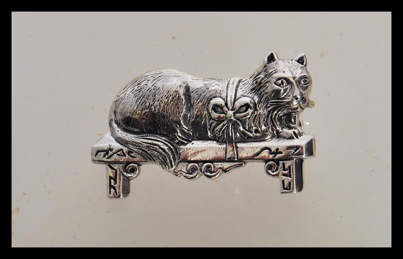 A stamped 925 silver brooch in the form of a cat sitting on a bench with a hinge pin to the verso.
