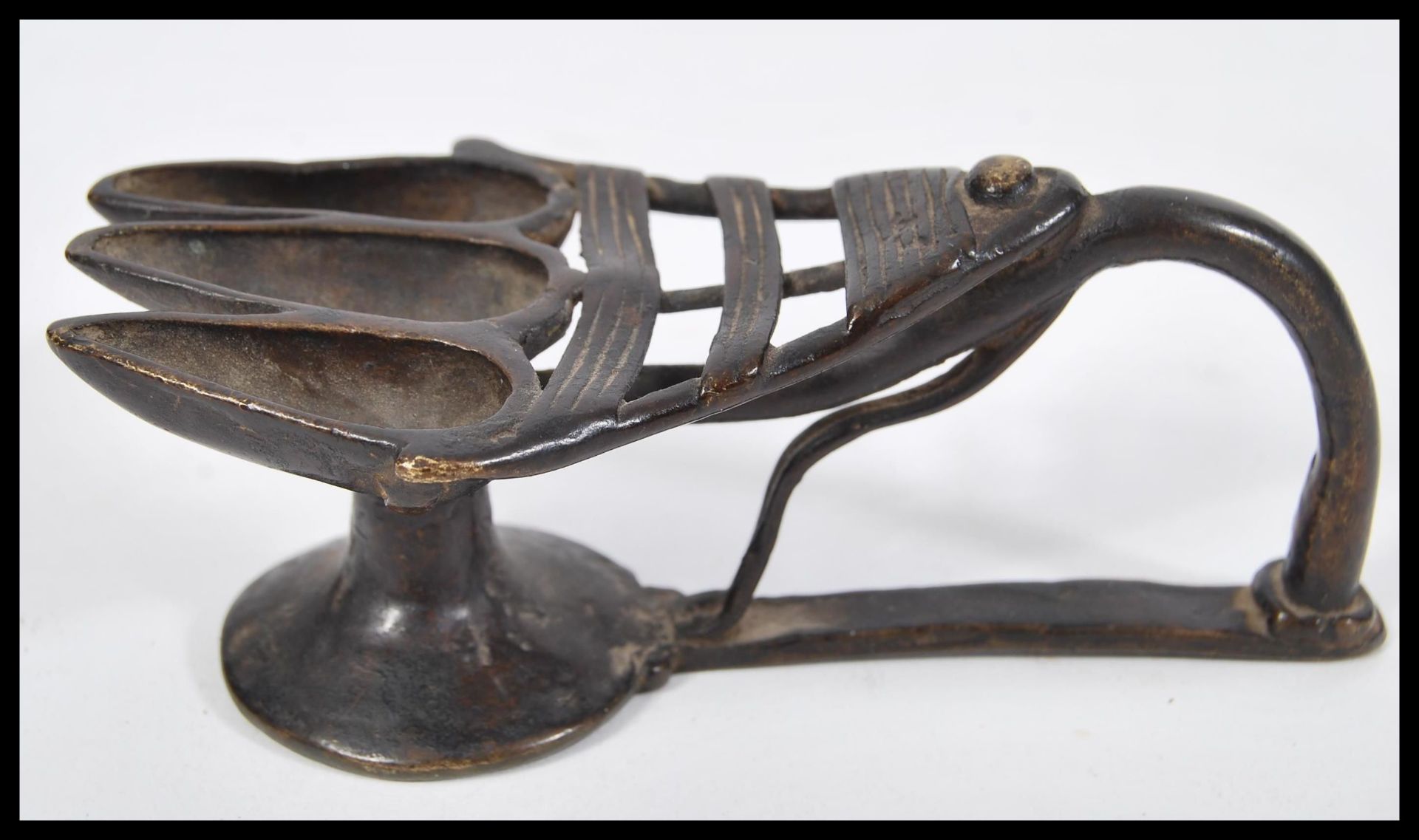 An 18th Century Indian bronze triple oil offering lamp having three section end with shaped handle.