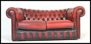 A 20th Century oxblood red leather chesterfield sofa with barrel rolled arms and button backed