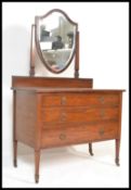 An early 20th Century mahogany dressing table chest raised on tapering legs with brass peacock and