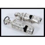 Two whistles to include a hallmarked silver whistle and a silver plated example with rococo chased