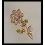 A stamped 750 18ct gold brooch in the form of a flower set with white, pink and green stones. Weight