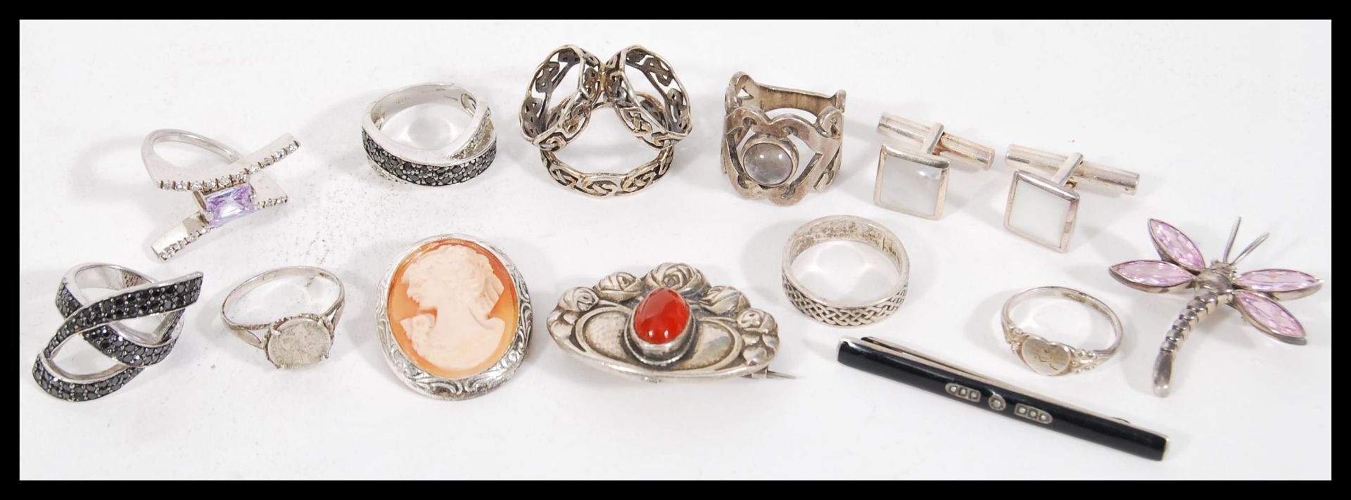 A selection of silver jewellery to include two cross over rings set with black accent stones, a coin