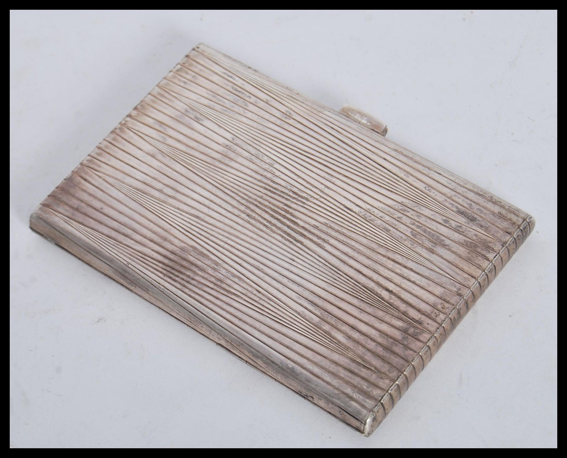 A silver white metal tests as silver cigarette case having a bark effect / backgammon type design to