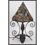 A 20th Century iron scrollwork table lamp, the lamp raised on four downward swept leaf base with
