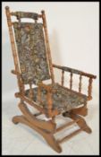An early 20th Century American rocker rocking chair having spindle gallery armrests raised on